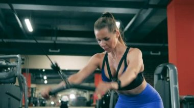 Kadın spor salonunda bir makineyle tatbikat yapıyor..