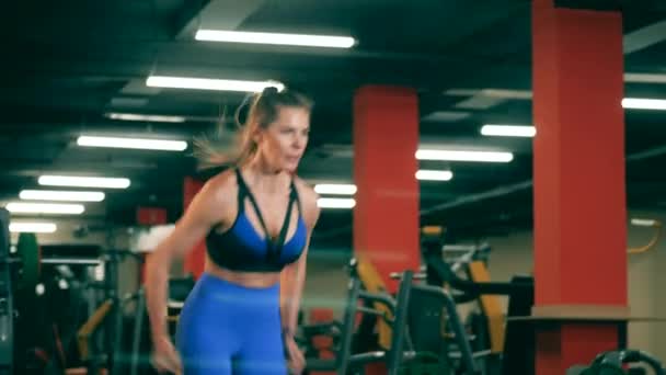 Junge Frau turnt im Fitnessstudio und springt auf eine Kiste. — Stockvideo