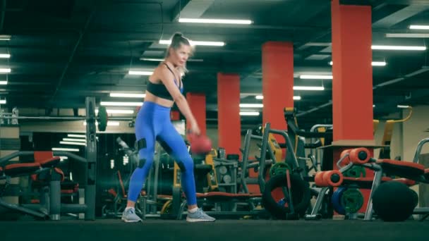Entrenamientos de mujeres fuertes con una pesebre en el gimnasio . — Vídeos de Stock