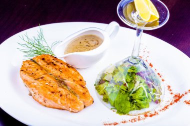 Beyaz plaka üzerinde yeşil salata ızgara somon steak