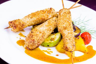 Fried chicken susam beyaz plaka üzerinde ızgara sebzeler ile süslenmiş ile