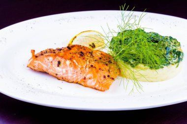 Patates püresi ve beyaz tabakta haşlanmış ıspanak ile ızgara somon