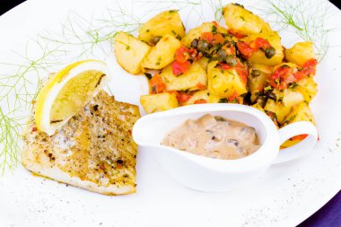 Kızarmış Balık beyaz plaka üzerinde fırında patates ile süslenmiş