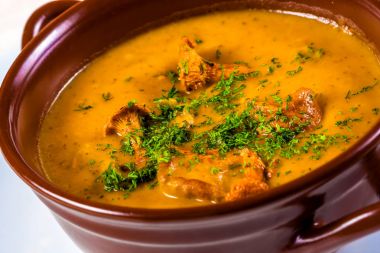 Chanterelles, patates ve otlar seramik tencerede krem çorbası