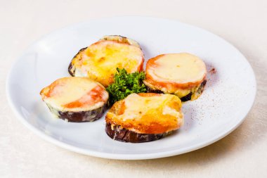 Domates ve peynirle beyaz plaka üzerinde fırında patlıcan