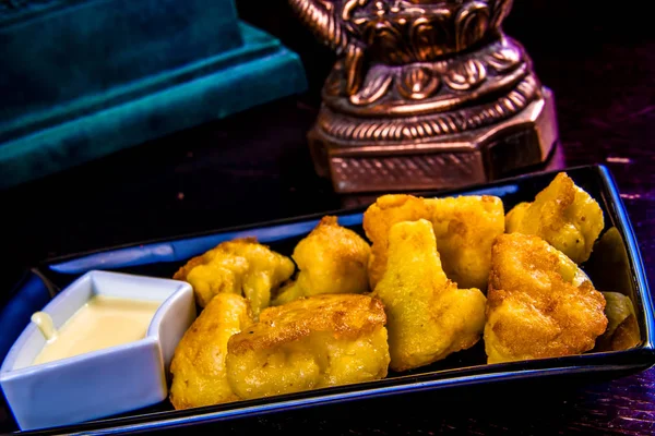 Derin kızarmış karnabahar siyah plaka üzerinde sos ile