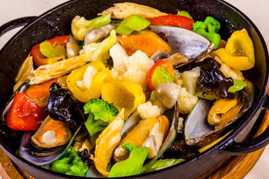 Dökme demir siyah tencerede sebzeli midye