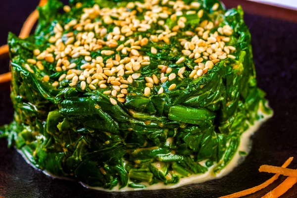 Siyah plaka üzerinde fındık sos ve susam tohumu ile Japon yosun salatası