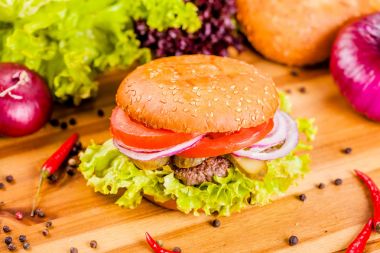 Hamburger biftek pirzola, domates ve soğan halkaları ahşap kesme tahtası ile
