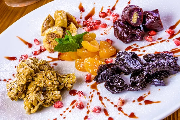 Dried fruits, sunflower seed brittle, walnut Georgian churchkhela on white plate