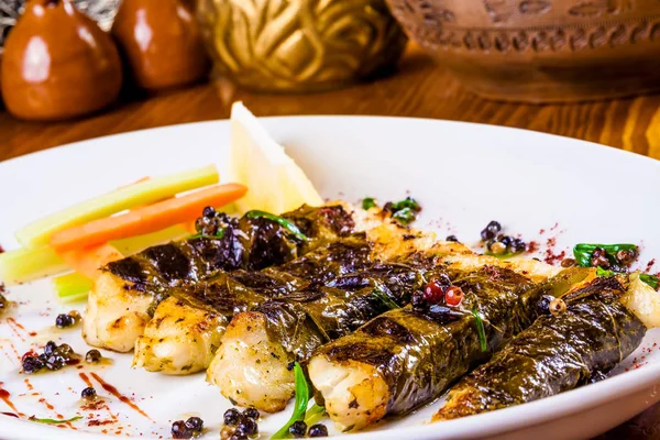 Beyaz plaka üzerinde üzüm yaprakları pişmiş pikeperch