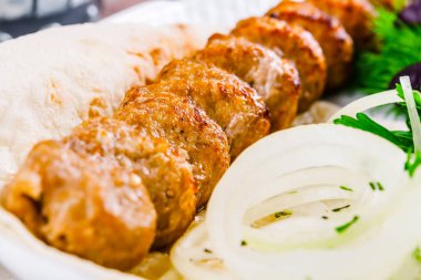 Koyun eti kebabı soğan ve otlar beyaz plaka üzerinde