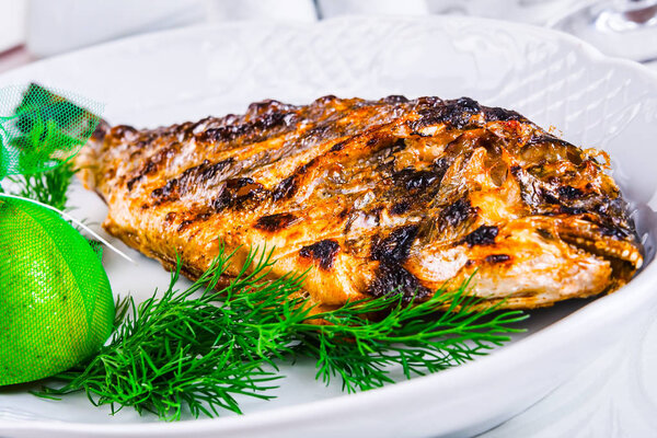 Grilled dorado fish on white plate