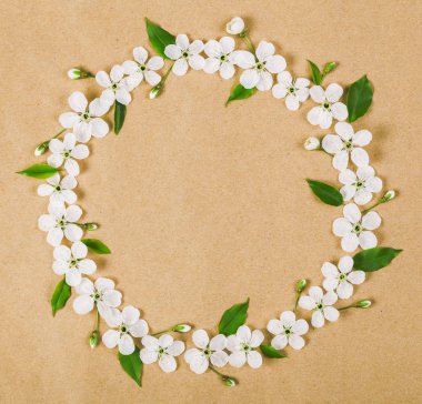 Yuvarlak kare çelenk beyaz bahar çiçekleri yapılmış ve yeşil kahverengi kağıt arka plan üzerinde bırakır. Üstten Görünüm. Düz yatıyordu.