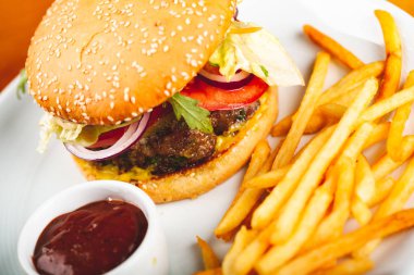 Fast food. Beyaz tabakta ev yapımı hamburger ve patates kızartması.