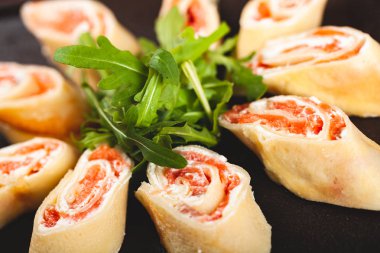 Siyah tabakta roka ile servis edilen somon ve krem peynirli krep (krep, blini)..