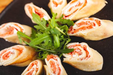 Siyah tabakta roka ile servis edilen somon ve krem peynirli krep (krep, blini)..