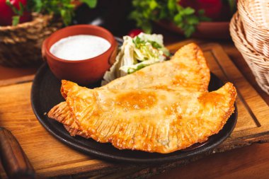 Geleneksel Kırım Tatar yemek çizelgeleri, kıyma ve siyah tabakta ekşi krema ile servis ediliyor..