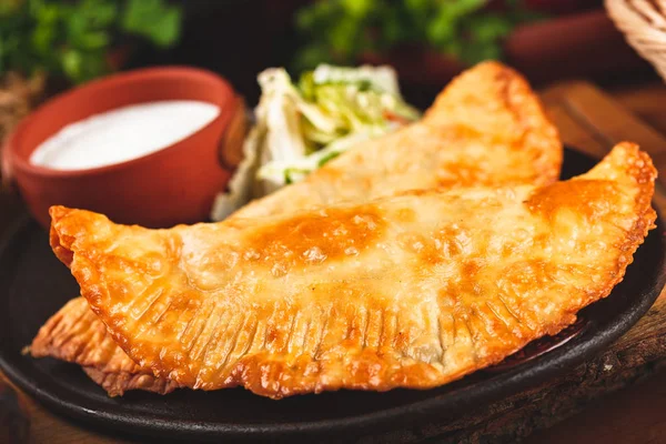 Geleneksel Kırım Tatar yemek çizelgeleri, kıyma ve siyah tabakta ekşi krema ile servis ediliyor..