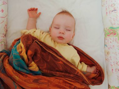 Bebek yatakta sırt üstü uyuyor.