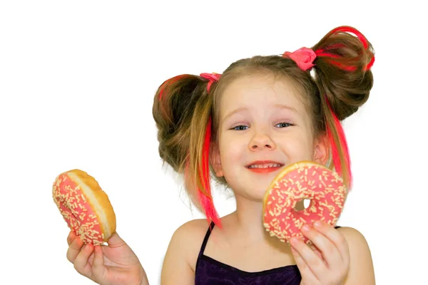 Маленькая девочка держит два пончика, как стаканы возле глаз — стоковое фото