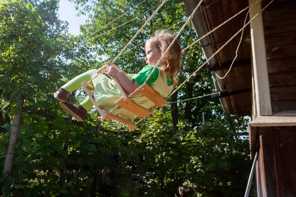 Enfant dans une robe vert clair est chevauchant une balançoire de corde — Photo