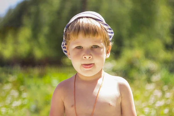 一个戴着条纹帽的男孩坐在阳光下 孩子在新鲜空气中晒日光浴 — 图库照片