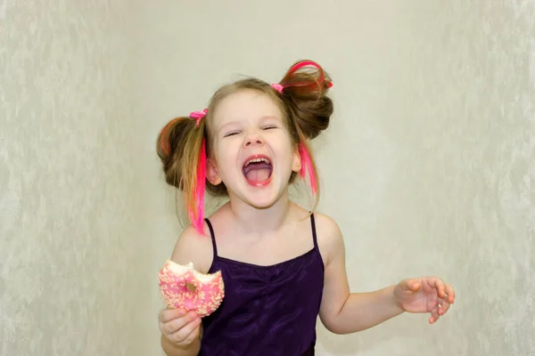 Neşeli bir kız pembe bir çörek yedikten sonra çığlık atıyor. Tatlılar çocukları arzuluyor. Kız partiye seviniyor..