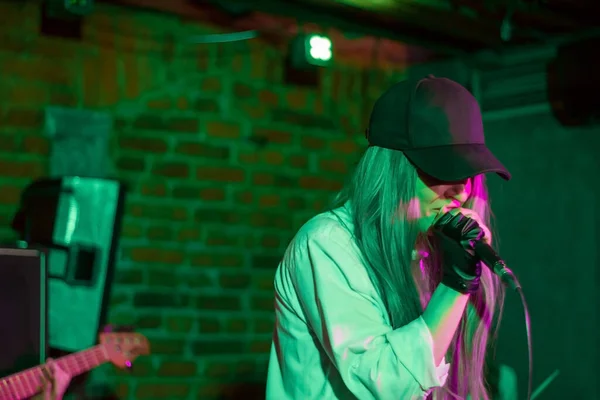 戴着帽子的年轻漂亮的姑娘在摇滚俱乐部里唱歌 年轻的乐队在夜总会 灵魂的音乐 — 图库照片