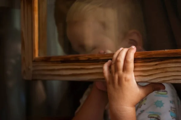 Małe Dziecko Boi Się Kary Chowa Się Ramą Okna Przerażony — Zdjęcie stockowe