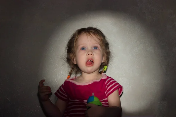 Küçük, şaşkın, ağzı açık bir kız duvardaki film projektöründen yansıyan dikdörtgen bir ışık çerçevesine karşı..