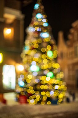 Noel ağacında hediyeler ve akşamları arka planda sarı ışıklar.