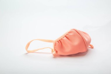 El yapımı kumaş bej yüz maskesi beyaz bir arka planda yatıyor. Yatay oryantasyon. Yüksek kalite fotoğraf