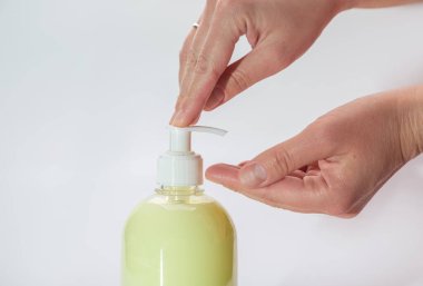 Eller sarı bir şişenin üzerine sıvı sabunla bastırır. Yatay oryantasyon. Yüksek kalite fotoğraf