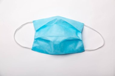 Tek kullanımlık mavi bir tıbbi maske beyaz bir arka planda yatıyor. Yatay oryantasyon. Yüksek kalite fotoğraf