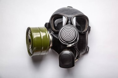 Siyah komuta gaz maskesi beyaz bir arkaplanda bir masada duruyor. Yatay oryantasyon. Kapat.