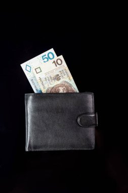 Para zloti banknotları siyah arka plandaki siyah bir cüzdandan sarkıyor. 10, 50 zl. Dikey yönelim. 