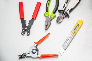 Beyaz arka planda elektrik tesisatı için araçlar. Ön planda kabloları söken bir striptizci. Kabloları, penseyi, tel kesiciyi, kesme bıçağını kesmek için bir alet. Yatay yönelim.