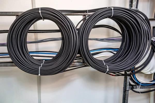 Cable management. Working wires, cables wound into a coil, a circle. Two rings of coiled wires, wire roll on the wall.. Horizontal orientation.