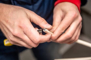 Kesik bir bıçakla kablo yalıtımı kesiliyor. Beyaz kablo, sarı bıçak. Yakın plan. Yatay yönelim. 