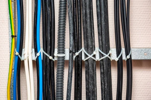 Câbles attachés avec des liens blancs sur l'échelle de câble. Noir, gris, jaune, blanc, fils de terre, câble ondulé. Gestion des câbles. Gros plan. Orientation horizontale . — Photo