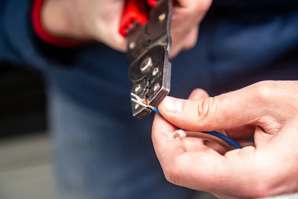 Work with the red tool for crimping wires and cables. Close-up. Horizontal orientation. — Stock Photo, Image