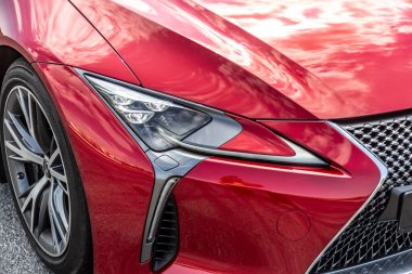 Güneşli bir günde radyatör ızgarası, far ve kırmızı bir arabanın tekerleği. Yakın plan. Yatay yönelim.