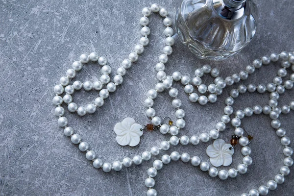 Una hebra de perlas y perfume sobre un fondo de piedra — Foto de Stock