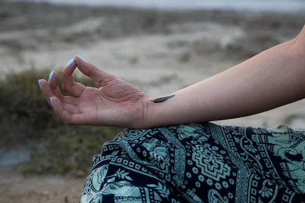 Χέρι μιας γυναίκας διαλογισμό σε στάση γιόγκα στην παραλία στο ηλιοβασίλεμα — Φωτογραφία Αρχείου