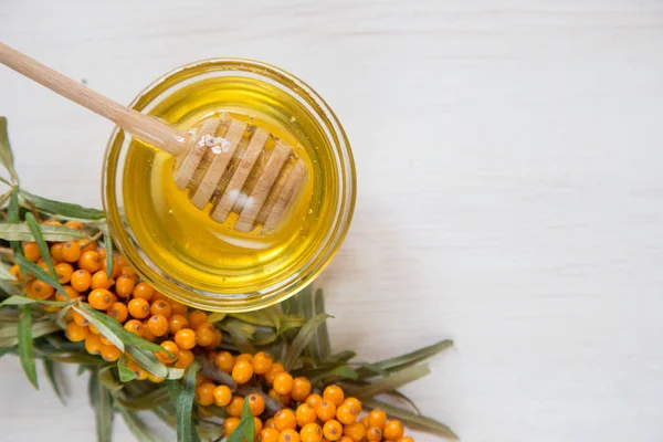 Sea buckthorn and honey on a light background. Selective focus — Stock Photo, Image