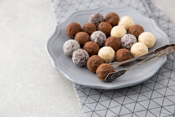 Verschiedene Schokoladentrüffel mit Kakaopulver, Kokosnuss und gehackten Haselnüssen auf einem Dessertteller — Stockfoto