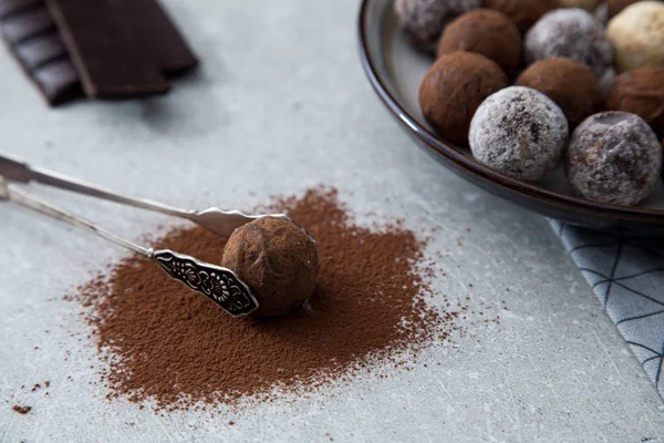Trufas de chocolate surtidos con cacao en polvo, coco y avellanas picadas en un plato de postre —  Fotos de Stock