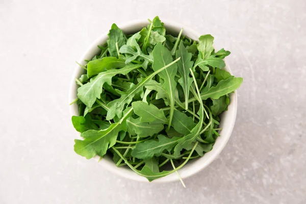 Fresh arugula salad on a grey stone background — Stock Photo, Image