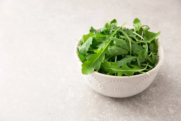 Salada de arugula fresca em um fundo de pedra cinza — Fotografia de Stock